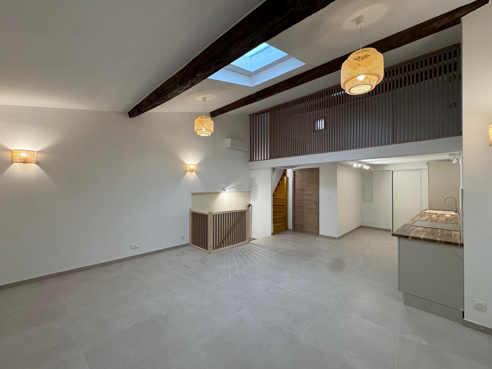 Après rénovation intérieure complète – séjour avec mezzanine, poutres apparentes, carrelage grand format, cuisine ouverte